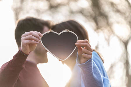 Portrait of a couple holding a heart-shaped blackboardの写真素材