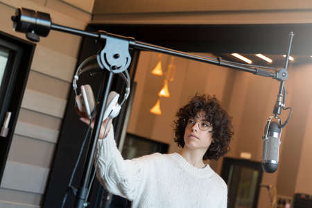 A young curly hair singer woman with glasses recording a song in a real studio