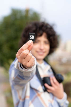 Curly hair woman showing an sd memory card to the cameraの写真素材