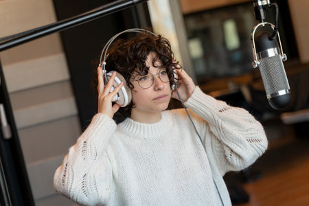 A young curly hair singer woman with glasses recording a song in a real studio