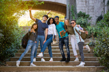 Group of young multiracial students waving at the camera on some stairsの写真素材