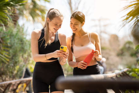 Two young women walking and looking at the phone while playing sports
