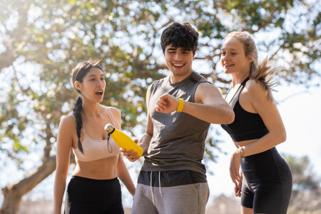 Three young people doing sports look at the smart watch and laugh in the parkの写真素材