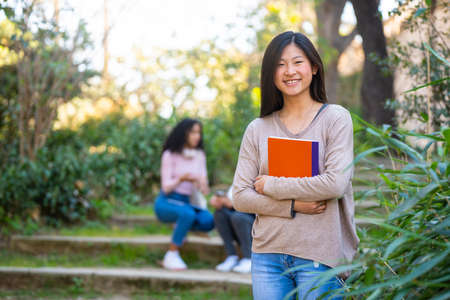 Young asian female student smiling and looking to the camera with a notebookの写真素材