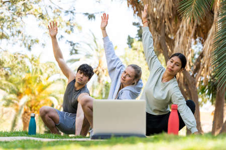 Three young people learning yoga and looking at the laptop. There are two women and one manの写真素材