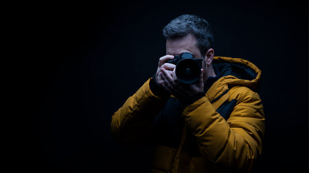 Photographer in a yellow coat taking a photo with a black background