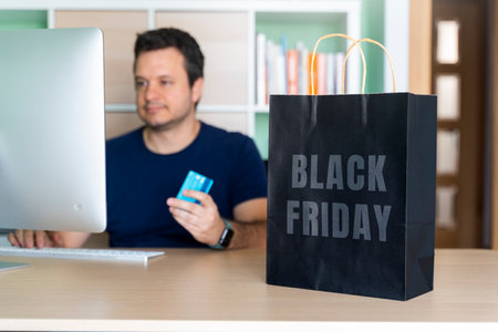 Man in his home office buying things online for black fridayの写真素材