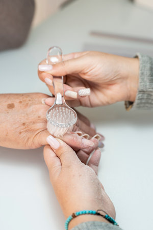 Real female manicurist cleaning a senior womans fingernail with a brush