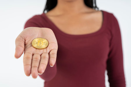 Young black woman showing a bitcoin coin to the camera on a white background.の写真素材