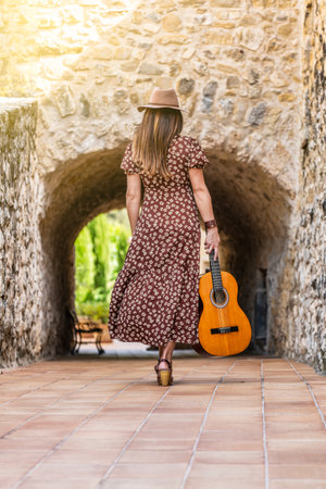 Woman walking with her guitar in a rural settingの写真素材