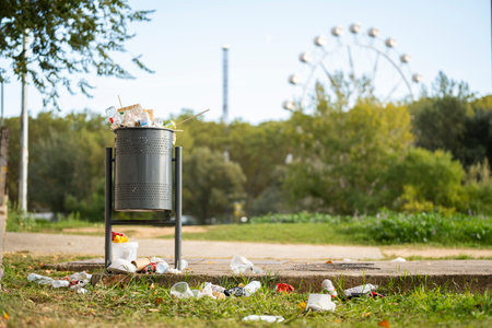 Landscape of a park with a trash can full of garbageの写真素材