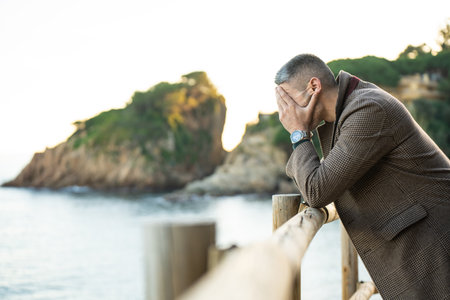 Sad man next to the sea with mountains on the backgroundの写真素材