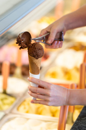Close-up of a woman preparing a chocolate flavored ice cream coneの写真素材