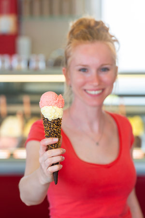 Redhead woman showing an ice cream to the cameraの写真素材