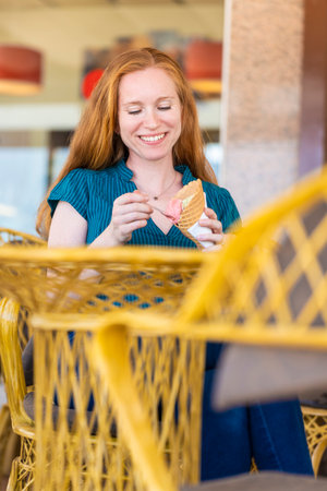 Redhead woman having a glass of ice cream on a terrace of an ice cream parlorの写真素材