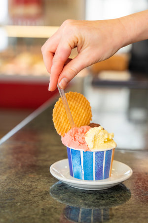 A tub of ice cream in two flavors and a cookieの写真素材