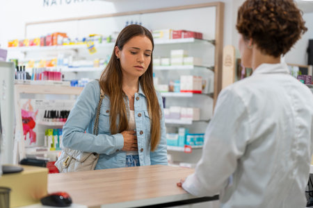 Young woman with a stomachache in a pharmacyの写真素材