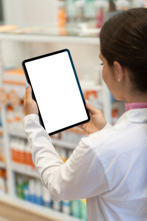 Female pharmacist looking at the screen of a digital tablet in the pharmacyの写真素材