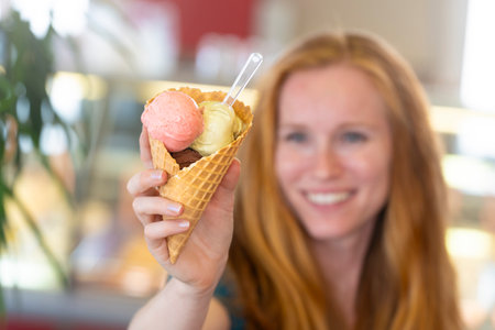 Redhead woman showing an ice cream to the cameraの写真素材