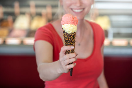 Unrecognizable woman showing an ice cream to the cameraの写真素材