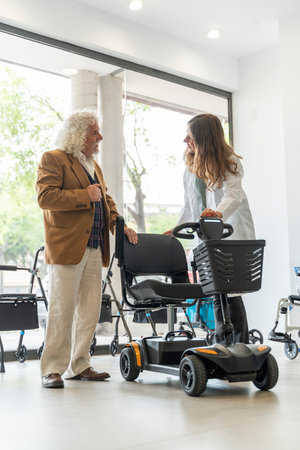 Older man in an orthopedic shop trying out an electric scooterの写真素材