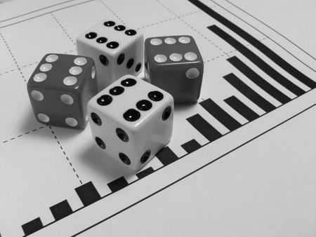 Black and white photo of four dices over a graph of increasing barsの写真素材