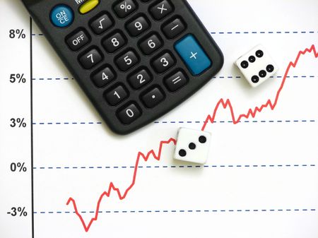 A calculator besides two dice on top of a stock market graph of increasing trendの写真素材
