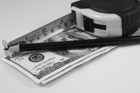 a measuring tape and a black pencil over bills of one hundred dollarsの写真素材