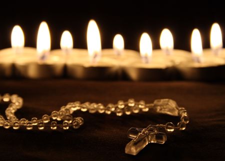 a crucifix in front of a row of candlesの写真素材