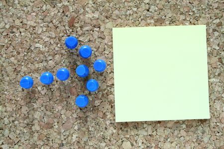 arrow made of blue pushpins pointing to a note on a cork board