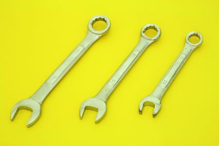 three wrenches on a yellow surface