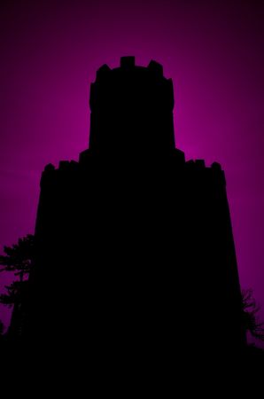 Moody silhouette of a castle against a dark purple sky.の写真素材