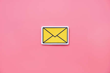 Yellow message sign or envelope icon against a pink backgroundの写真素材