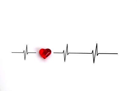 Light-reflecting red heart of glass with curves of cardiac cycles, pulse or heartbeats, electrocardiogram (ECG) white background, copy spaceの写真素材