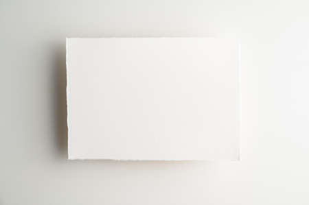 Blank backdrop for notes, to-do lists, messages, reminders, notices or notepapers. Blank sheet of white handmade paper on light background. Table top view, flat lay, copy space.の写真素材