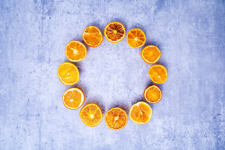 Christmas wreath or Advent crown minimalism: dried orange slices in bright colors, arranged in a circle on a background with concrete look. Table top view, flat lay, copy space.の写真素材