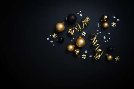 Christmas decorations in black and gold: Baubles, stars and ribbon on a black background. Table top...