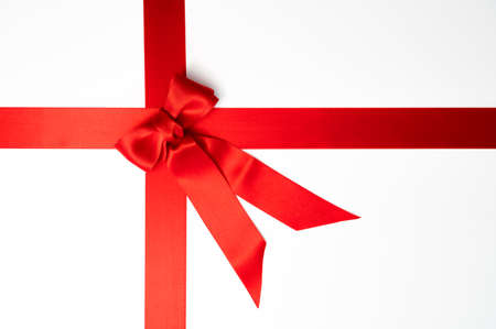 Christmas gift, Valentine's Day or Black Friday concept: Red gift ribbon tied in a bow on a white background. Table top view, flat lay, copy space.の写真素材