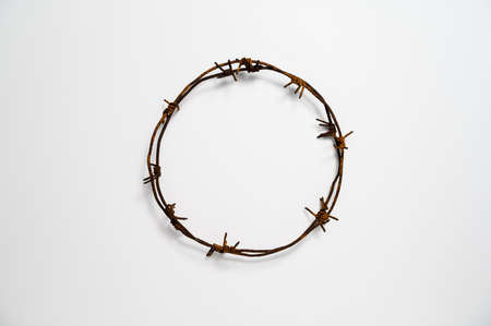 Contemporary Crown of Thorns or Good Friday concept: A wreath of rusted barbed wire against white background. Table top view, flat lay, copy space.の写真素材