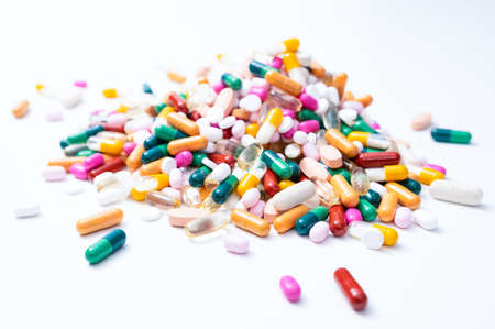 Pile of drugs with a variety of colorful tablets, pills, capsules and dragees on white background. Health service, care, pharmacy or pharmaceutical industry concept.の写真素材