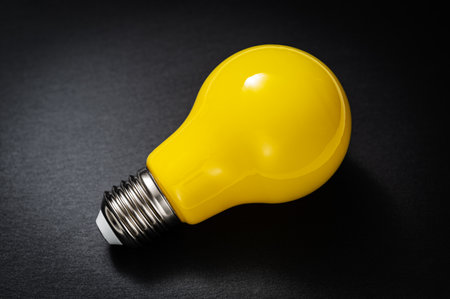 Yellow lightbulb on black slate background. Inspiration, idea, innovation or creativity concept.の写真素材