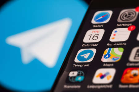 Leipzig, Germany - December 15, 2021: Telegram instant messaging service concept. Smartphone screen displaying various application icons. In the background a blurred Telegram logo.のeditorial素材
