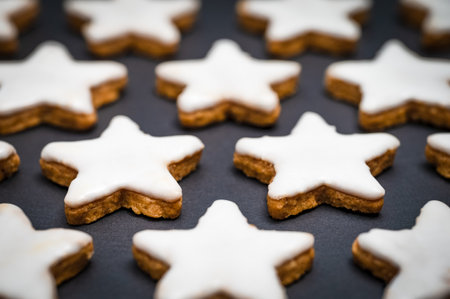 Christmas pastry recipe. Freshly baked cinnamon stars with icing or sugar glaze on a background made of black slate.の写真素材