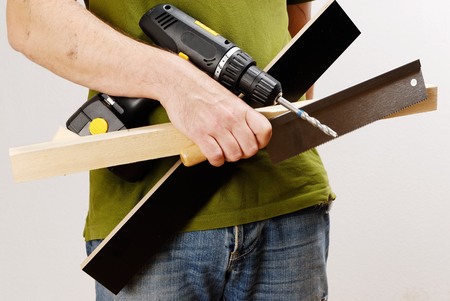 A man with a cordless screwdriver and wood in his hand