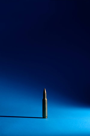 A single bullet is standing on a blue groundの写真素材