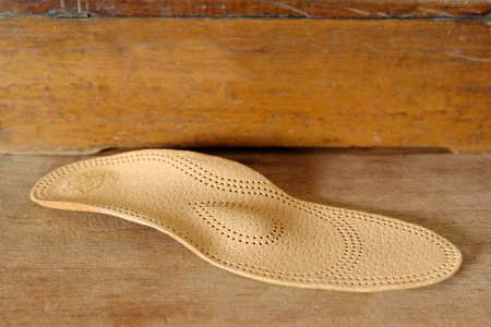 Orthopedic arch support made from leather on a wooden groundの写真素材