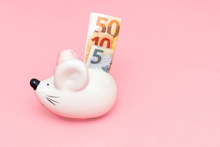 A white piggy bank with bank notes on pink backgroundの写真素材
