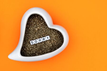 A ceramic heart with the text SORRY isolated on orange backgroundの写真素材