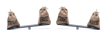 A beam scale with two canvas bags and the words STRENGTHS and WEAKNESSESの写真素材