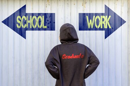 A young woman in front of two blue guideposts with yellow text SCHOOL and WORKの写真素材